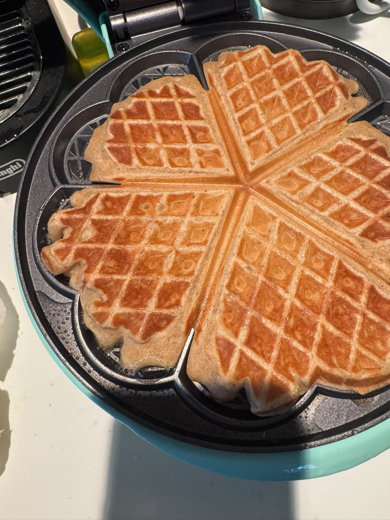 Vier frisch gebackene Waffeln im Waffeleisen, in Herzform angeordnet
