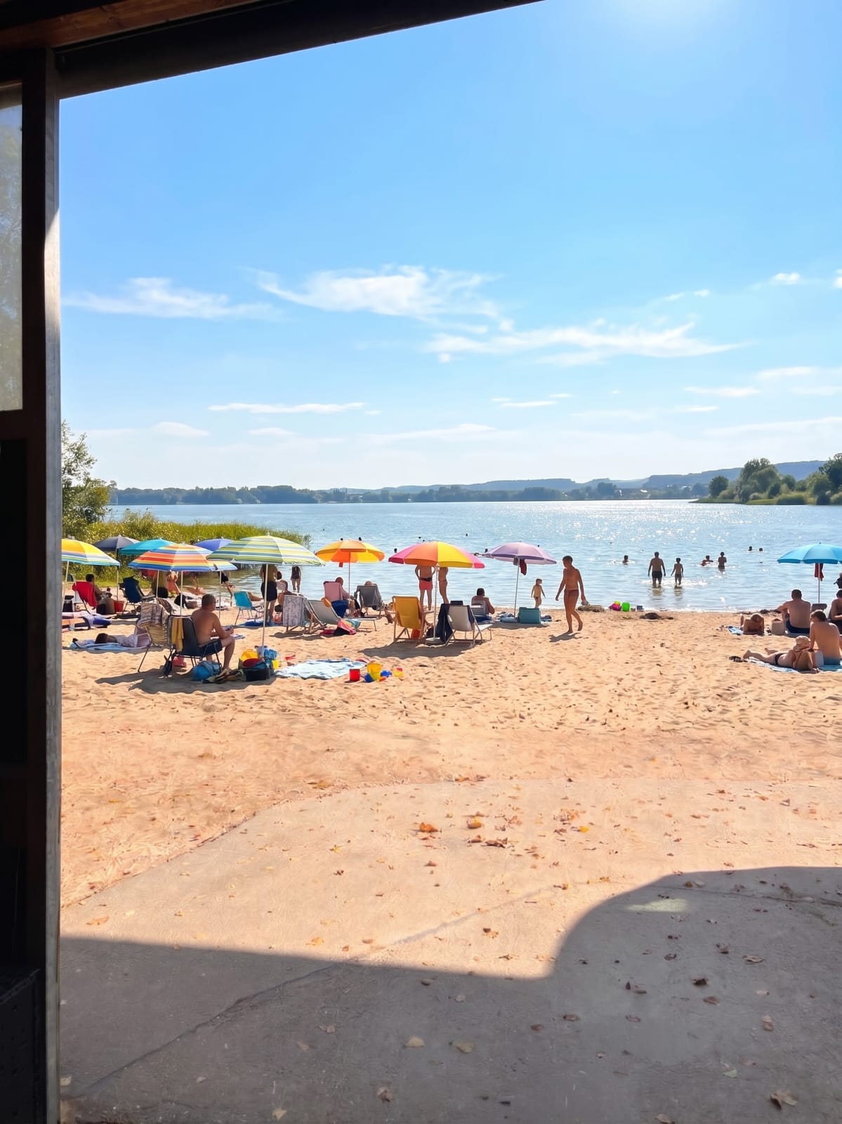 Badestrand mit Sonnenschirmen und Badenden, durch eine offene Tür betrachtet
